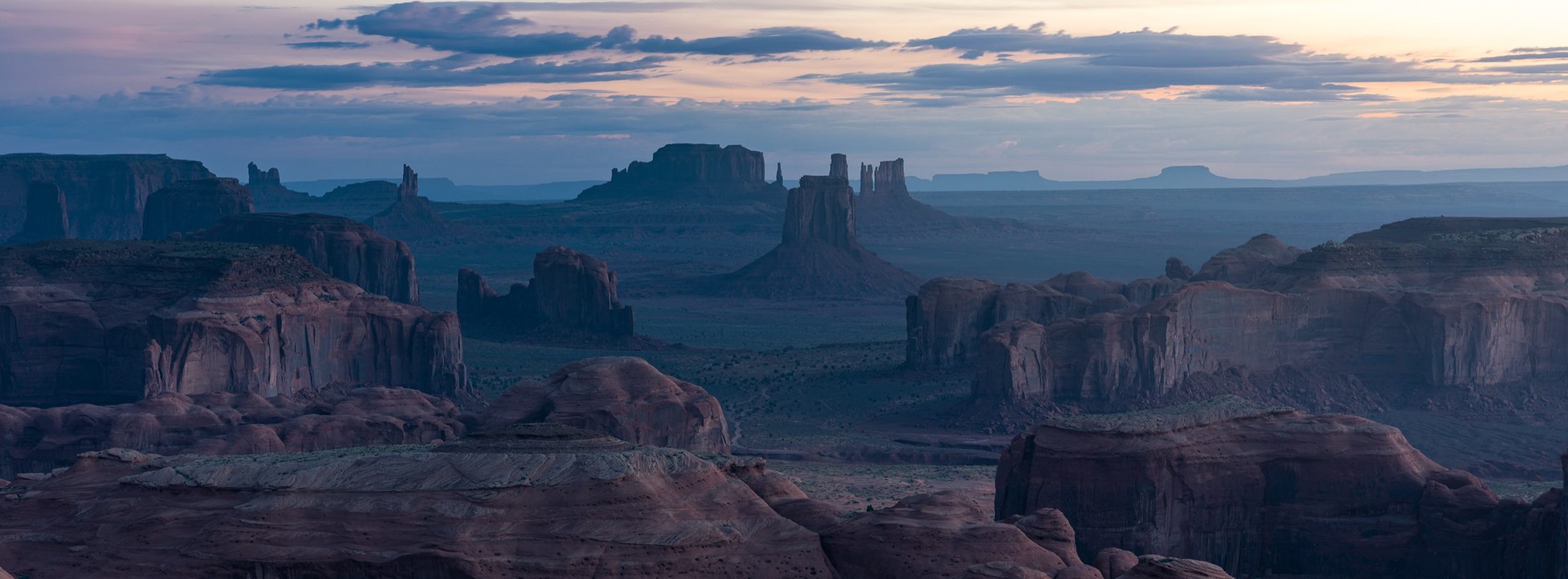 Layers of desert buttes in pastel sunrise light, seen from Hunt’s Mesa